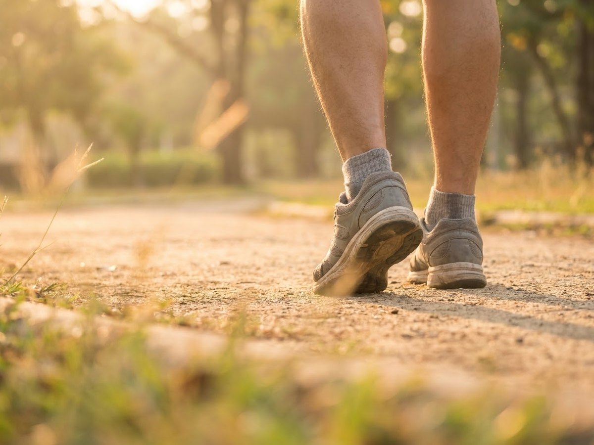 Runner seen from behind on a park path, ankles rolling slightly inward mid-stride
